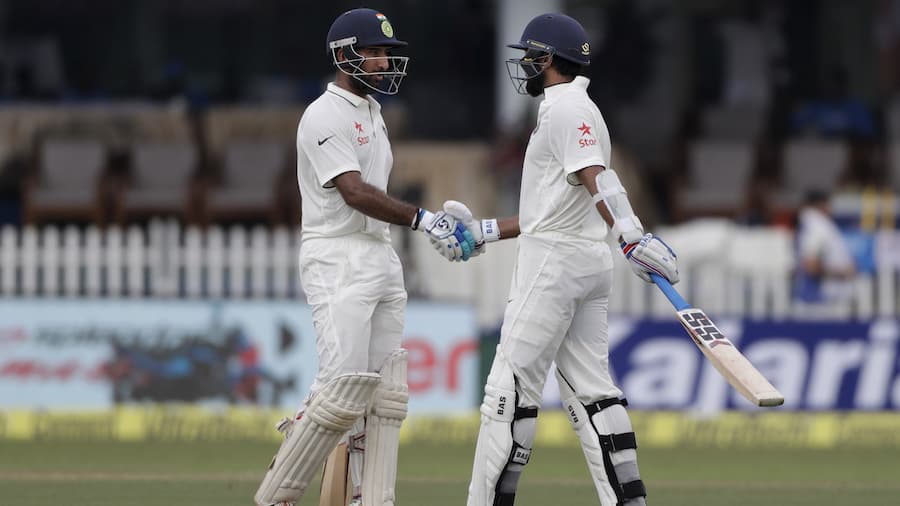 India's Cheteshwar Pujara, right, shakes hand with Murali Vijay after Vijay made half century against New Zealand during their first test match in Kanpur, India , Thursday, Sept. 22, 2016. (AP Photo/ Tsering Topgyal)