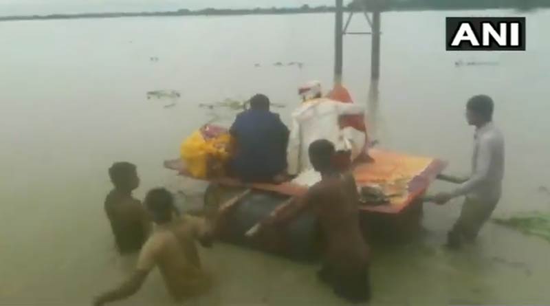 Newly married couple cross flooded road using makeshift boat