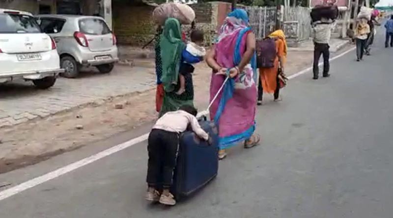Migrant workers son sleeping on a suitcase being wheeled by his mother