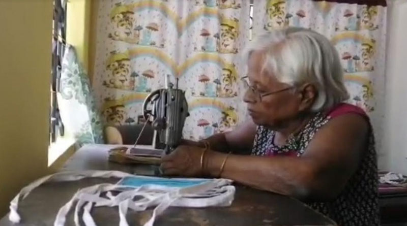 A 70 up old woman ignoring her cancer pain, making mask for others